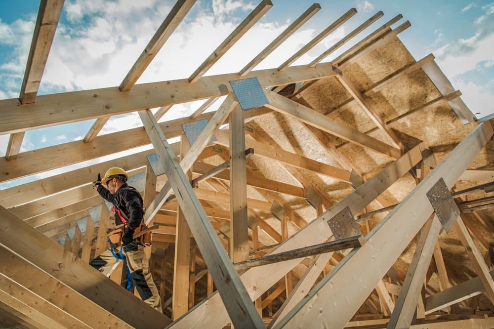 Carpenter working among engineered roof trusses on an ACE framing project